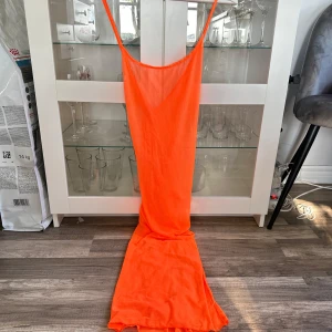 Neon orange strandklänning med slits - En neon orange strandklänning med korsad rygg och slits på sidan i storlek XL som endast är testad. Köptes för nypris 150kr! FÖRST TILL KVARN!