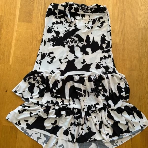 Svartvit kort volangklänning - Vit och svart off the shoulder klänning från Brasilien! Säljer då den inte riktigt är min stil. Aldrig använd 