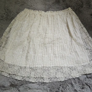 Spetskjol - Superfin vit kortkjol med plisserad design och vacker spets med blommönster. Kjolen har elastisk midja och ett skirt lager som ger en romantisk vibe. Storlek M men passar S också. Skriv om du har funderingar.