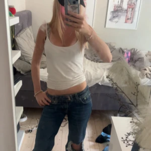 Blå bootcut jeans med slitna knän - Säljer ett par blå bootcut jeans med rejält slitna och trasiga knän. Jeansen har låg midja och klassisk femficksmodell. Från lager 157.