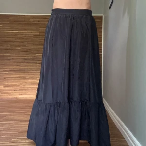 Svart långkjol med volang - En svart superfin långkjol med volang nertill. Kjolen har en luftig och flowy passform som ger en avslappnad vibe. Perfekt att styla med en crop top eller stickad tröja för en cool look. Vet tyvärr inte vart den är ifrån eller vilken storlek för lappen är bortklippt. Men jag är strl S och är ca 168cm💕