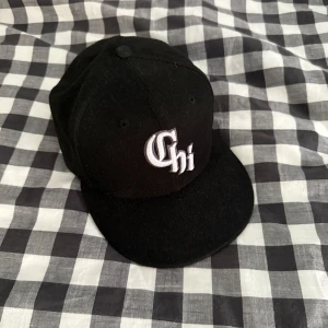 Svart New Era 59FIFTY keps Chi - Snygg svart keps från New Era 59FIFTY med broderad vit 'Chi' framtill. Klassisk modell med rak skärm och broderade ventilationshål. MLB-logga baktill och New Era-logga på sidan. Perfekt för dig som gillar streetstyle.