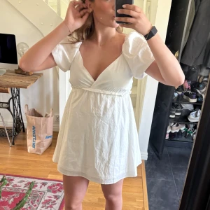 Vit kort omlottklänning med puffärm - Supersöt vit kort klänning med omlott-v-ringning och puffiga korta ärmar. Klänningen har en flowy passform och markerad midja. Jag är 178😊😊