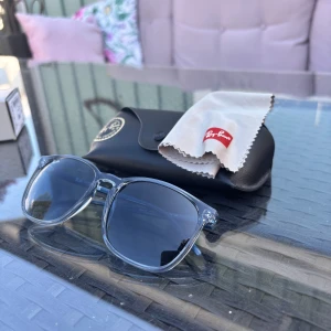 Ray-Ban transparenta solglasögon - Snygga äkta Ray-Ban solglasögon med transparent/fylld båge och mörkblå glas. Kommer med originalfodral och putsduk. Perfekta för att lyfta din stil under soliga dagar. Tveka inte på att skriva vid fundering 🙌