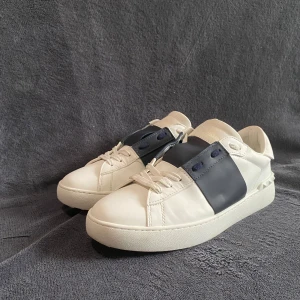 Valentino Garavani sneakers navy - Säljer ett par snygga Valentino Garavani open skor. Perfekta för dig som vill ha en stilren look. De är knappt använda, normala i storleken, dustbag, skolåda ingår. Skriv vid frågor eller funderingar!