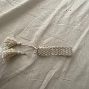 Beige armband från Dior med tofsar - Snyggt beige armband från Dior med broderad text 'Christian Dior Jadoe’. Pris kan diskuteras i dm 