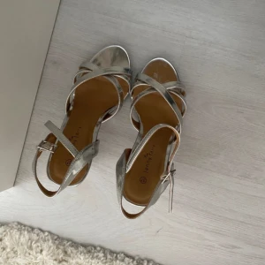 Silvriga Klackskor  - Super snygga silvriga eleganta klackskor! Dem är använda ett fåtal gånger och som bilderna visar är dem i ett bra men använt skick! Bara skriv om ni har frågor. Dem är ca 10cm men väldigt bekväma att gå i. Inga problem för nybörjare 😅