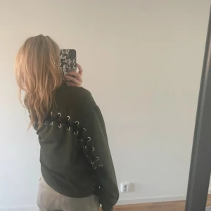 Olivgrön bomberjacka med snörning - Säljer en olivgrön bomberjacka med cool snörningsdetalj längs ryggen och sidorna. Jackan har dragkedja framtill och en avslappnad passform. Storlek S från HM divided (gammal kollektion) Bra skick! Pris kan diskuteras❤️