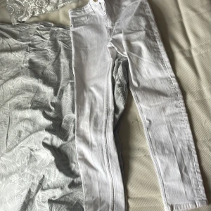Vita skinny jeans high waist - Säljer ett par vita skinny jeans med hög midja och klassisk femficksmodell. Jeansen är i stretchigt denimtyg och har dragkedja och knapp framtill. Perfekta för dig som gillar en tight passform och vill ha en clean look.