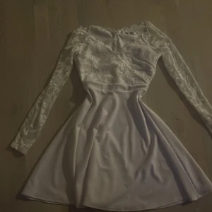 Long Sleeve Skater Dress - Klänning från Goddiva. - Mjuk, stretchig kvalitet. - V-ringad halsringning. - Knapp. - Markerad midja. - Dold dragkedja baktill. - Transparent på ärmarna. - Foder upptill. - Längd från axel bak: 83 cm i storlek S.