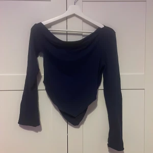 Mörkblå långärmad topp från SHEIN - Säljer en mörkblå långärmad topp från SHEIN med bred, offshoulder-ringning och spetsig nederkant framtill. Snygg och enkel modell som passar perfekt till jeans eller kjol. Toppens material känns mjukt och stretchigt. Längd 46 cm. 