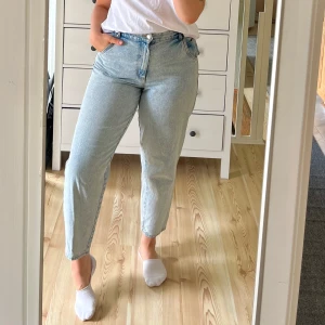 Mom jeans från H&M - Säljer ett par fräscha ljusblå mom jeans från H&M i storlek 40. Jeansen har hög midja, raka ben med lite avsmalnande passform. Tillverkade i bomull, med snygg detalj längst ner på benen!🌸Normal i storlek!☀️