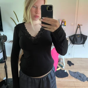 Svart långärmad topp med spets - Svart långärmad topp med djup v-ringning och bred spetskant runt halsen. Snygg och enkel modell som sitter figurnära och har en feminin touch med den blommiga spetsen. Perfekt att styla med jeans eller kjol för en trendig look. Skriv vid frågor❤️