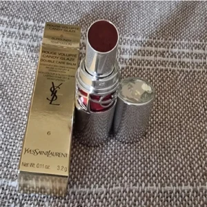 YSL Rouge Volupté Candy Glaze 6 - YSL Rouge Volupté Candy Glaze Double Care Balm i färgen 6 Burgundy Temptation. Lyxigt läppstift med intensiv burgundy-nyans, glansig finish och återfuktande formula. Snygg silverhylsa med YSL-logga och detaljer i rött. Oanvänd,  endast uttagen för att ta bilder.