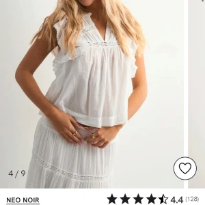 Vit blus med volang från Neo Noir - Superfin vit blus från Neo Noir med volangdetaljer och v-ringning. Blusen är ärmlös och har broderade partier samt en luftig, lätt och flowy passform. Perfekt för en fräsch och somrig look med romantiska vibbar.