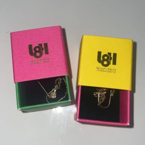 Guldiga örhängen från L8Hasselblad - Guldiga örhängen från L8Hasselblad. De har en minimalistisk kedjedesign med små, runda detaljer längst ner. Kommer i färgglada originalaskar, en rosa och en gul. Perfekta för dig som gillar stilrena och trendiga smycken.