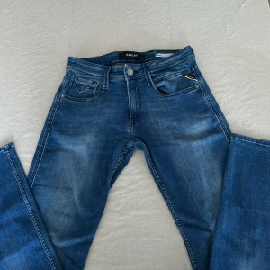 Replay Anbass slim fit jeans blå - Snygga blå Replay Anbass jeans i storlek 27 men passar både 28 och 29 också slim fit med klassisk femficksdesign och coola slitningar. Jeansen har medelhög midja och raka ben, tillverkade i mjukt denimtyg. Perfekta för dig som gillar en stilren och modern look.
