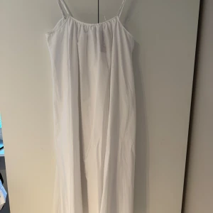 Vit flowy klänning från NA-KD - Superskön vit klänning från NA-KD i flowy bomull. Den har smala axelband och en avslappnad passform som ger en luftig känsla. Perfekt för varma dagar när du vill ha något enkelt men ändå snyggt. Ordinarie pris 699kr