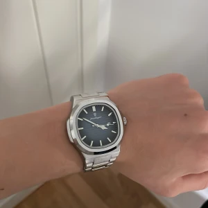 Silverfärgad Poedagar klocka med blå urtavla - Rostfritt stål bra kvalitet. Ordinarie pris 800kr. Du får med mer länkar och en grej till att fixa sätta på och ta av dem. Använd 1 gång.