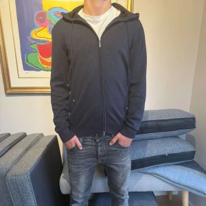 Mörkblå ziphoodie från Gran Sasso - Snygg mörkblå zip hoodie från Gran Sasso med dragkedja framtill och huva med snörning. Tröjan är stickad och gjord på 100% lamm ull (bästa kvalitet). Nyskick. Otroligt eftertraktad modell. Passa på då denna kommer gå åt fort. Priset ej hugget men snabba affärer kommer att prioriteras. Hör gärna av er vid vidare funderingar 🫶🏻