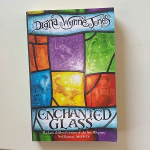 Enchanted Glass - Färgstark och magisk bok med ett omslag som påminner om glasmålningar. Perfekt för dig som gillar äventyr och mystik! Boken har ett citat från Neil Gaiman och är i begagnat skick med lätt slitage på hörnet.
