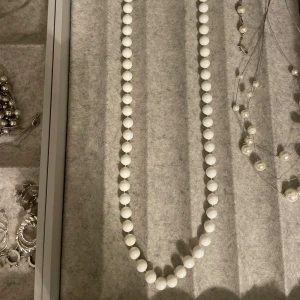 Vitt pärlhalsband vintage - Snyggt halsband med runda vita pärlor som är jämnt fördelade längs hela halsbandet och har en enkel knäppning. 