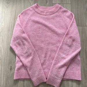 Rosa stickad tröja med rund hals - Mysig rosa stickad tröja med rund hals och ribbade muddar vid ärmslut och nederkant. Tröjan har en enkel och clean look, perfekt att matcha med jeans eller kjol. Super mysig nu till hösten när det blir kyligare ute.