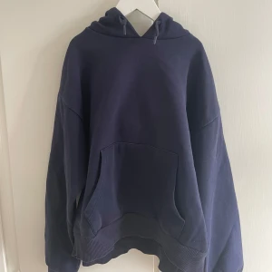 Mörkblå hoodie med huva och ficka - Mörkblå hoodie med stor känguruficka framtill och justerbar huva med snörning. Tröjan har ribbade muddar vid ärmslut och nederkant. Mycket skön och fin. 