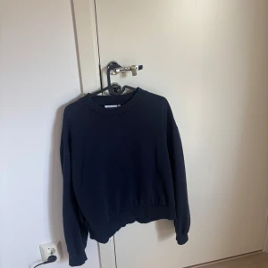 Oversized mörkblå sweatshirt - En oversized mörkblå sweatshirt med rund hals och långa ärmar. Tröjan har en enkel och clean look utan tryck eller mönster, perfekt för en chill och avslappnad stil. Mjuk och skön, passar till jeans eller kjol för en casual vibe.