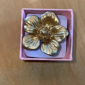 Guldig blomring i presentask - Säljer en stor ring med en blomma på från Olympia. Ingen storlek. Nypris 450:- 🌸💕