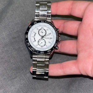 Silverfärgad klocka från Regal - Snygg silverfärgad klocka från Regal med vit urtavla och tre mindre urtavlor för extra funktioner.  Perfekt för den som gillar en stilren och funktionell design. Den har en liten spticka på bild 4 så kan man se den. Men  den är ungefär omärkbar.