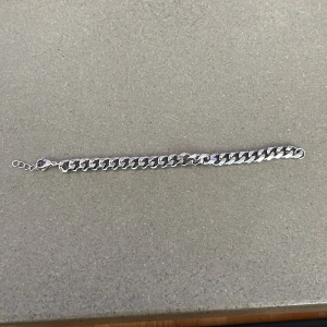 Kedjearmband i silverfärg - Stilrent armband med breda, platta länkar i silverfärg. Klassisk kedjedesign med justerbar längd och karbinhake. Perfekt accessoar för att ge din outfit en cool och modern touch. ÄKTA!  