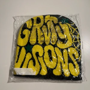 Gravy Visions gul och svart mössa - Gul/svart/grön Stickad mössa från Gravity Visions en Sida står det gravity visions på den andra finns det ett gult spindelnät
