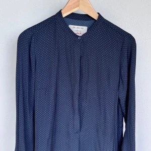 Mörkblå prickig skjorta Bondelid - Snygg mörkblå skjorta från Bondelid med små ljusa prickar över hela tyget. Skjortan har lång ärm, knäppning framtill och en enkel, stilren design. Perfekt för dig som gillar klassiska men ändå trendiga plagg.