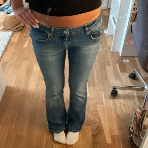 Blå bootcut jeans från ONLY - Snygga blå jeans från ONLY med låg midja och bootcut-ben. Jeansen har klassiska fem fickor, ljus tvätt och sitter tajt upptill med lite utsvängda ben. Perfekta för dig som gillar en retro vibe och vill ha ett par jeans som framhäver figuren.