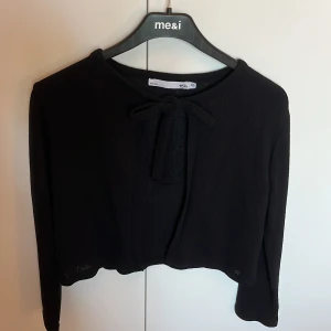 Svart kofta med knyt från 157 - Svart kofta från 157 med långa ärmar och snygg knytning framtill vid halsen. Materialet är stickat och har en lätt struktur. Klor för ungefär ett år sedan men fortfarande ganska bra kvalitet. Säljer då den dock börjat bli lite liten.😊