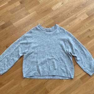 Grå stickad tröja från lager 157 - Mysig grå stickad tröja från laget 157 i storlek M. Tröjan har en rund halsringning och långa ärmar med ribbade muddar. Den är ganska knottrig. Du står för frakten, vid mer info skriv