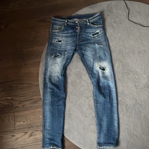 Blå slitna skinny jeans med hål - Säljer ett par blå skinny jeans med slitningar och hål på låren och knäna. Jeansen har en tvättad look och detaljer som ger en cool, avslappnad vibe. Perfekta för dig som gillar streetstyle och vill sticka ut.