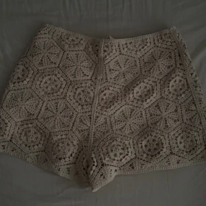 Beige virkade shorts med mönster - Superfina beige virkade shorts med unikt geometriskt mönster. De har en snygg, lite lös passform och är perfekta för varma sommardagar. Materialet är bomull och de känns både luftiga och trendiga. Perfekt att styla med en enkel topp eller bikini. köptes för ca 3 år sen på H&M. Säljes för alldeles för små. Små defekter men inget stort eller man tänker på.
