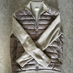 Moncler cardigan - Snygg grå cardigan från Moncler med quiltad front och stickade ärmar. dragkedja framtill, två fickor med dragkedja, Säljes för den börjar bli för liten! 
