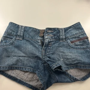 Blå jeansshorts - Snygga blå jeansshorts med låg midja i storleken XXS/32. Framtill finns dubbla knappar och dragkedja.
