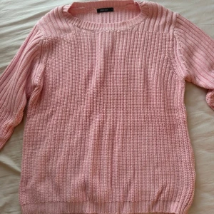 Ljusrosa stickad tröja  - Supermysig ljusrosa stickad tröja med grovstickad struktur och ribbade detaljer vid hals, ärmslut och nederkant. Tröjan har rund hals och långa ärmar, perfekt för att hålla sig varm och ändå se söt ut. Passar dig som gillar chill och comfy vibes.