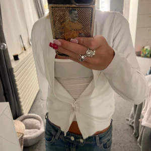 Vit kofta  - Säljer en söt vit kofta från C i storlek XS. Koftan har lång ärm, smal passform och knäpps framtill med en knapp. Perfekt att slänga över ett linne eller topp för en clean och fräsch look.