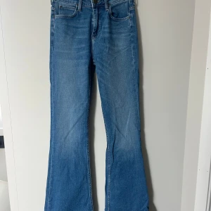 Blå bootcut jeans från Lee - Snygga blå jeans från Lee med klassisk bootcut-passform. Jeansen har fem fickor, Lee-logga på bakfickan och läderpatch i midjan. Tillverkade i mjukt denimtyg som gör att det är ett par bekväma snygga jeans.  Storlek w27 L33