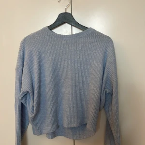 Ljusblå ribbad tröja från H&M - Supermjuk ljusblå ribbad tröja från H&M med lång ärm och relaxed fit. Perfekt för dig som gillar en enkel men snygg stil. Tröjan har rund halsringning och är gjord i ett stickat material som känns skönt mot huden. Nästan aldrig använd!