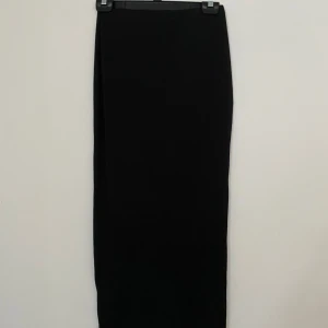 Svart långkjol från SHEIN XS - Svart långkjol från SHEIN i storlek XS. Kjolen har en rak och enkel design utan mönster eller detaljer, tillverkad i mjukt och stretchigt syntetmaterial. Perfekt för dig som gillar minimalistisk stil och vill ha en klassisk svart kjol i garderoben.