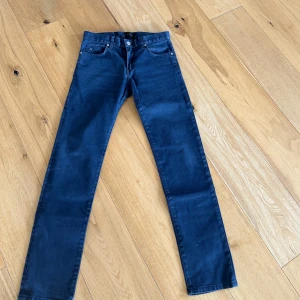 Mörkblå skinny jeans J.Lindeberg - Snygga mörkblå skinny jeans från J.Lindeberg med klassisk femficksdesign och diskret JL-logga på fickan. Jeansen har smal passform och raka ben, tillverkade i stretchig denim för extra komfort. Perfekta för dig som gillar stilrena och moderna jeans.