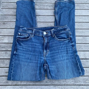 Blå raka jeans från H&M - Snygga blå jeans från H&M i slim fit-modell med justerbar midja. Klassisk femficksdesign och normalhög midja. Perfekta för dig som gillar en smalare passform och vill ha ett par stilrena jeans till vardags.