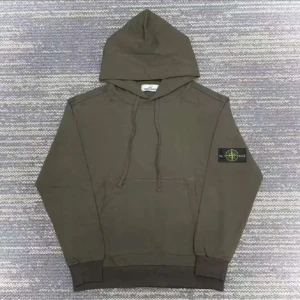Stone Island grön hoodie med patch - Säljer en grön hoodie från Stone Island med klassisk patch på vänster ärm. Tröjan har huva med snörning, magficka och ribbade muddar. Perfekt för dig som gillar streetwear och vill ha en clean look med snygga detaljer.