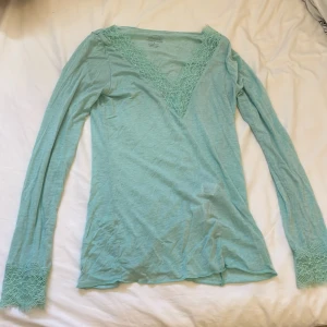 Mintgrön v-ringad topp med spets från intimissmi  - Säljer en supersnygg mintgrön långärmad topp från Intimissimi i ultralätt kashmirblandning. V-ringad med bred spetskant runt halsen och vid ärmsluten som ger en extra touch. Perfekt för dig som gillar mjuka material och vill ha en feminin vibe. Säljer pga av nästan ingen användning och att den är för stor. Jätte snygg tröja ifrån intimissmi i storlek S. Skriv om ni undrar något!💗